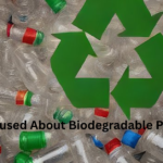 A pile of clear plastic bottles with colorful caps, overlaid with a large green recycling symbol and the text "Confused About Biodegradable Plastic?"